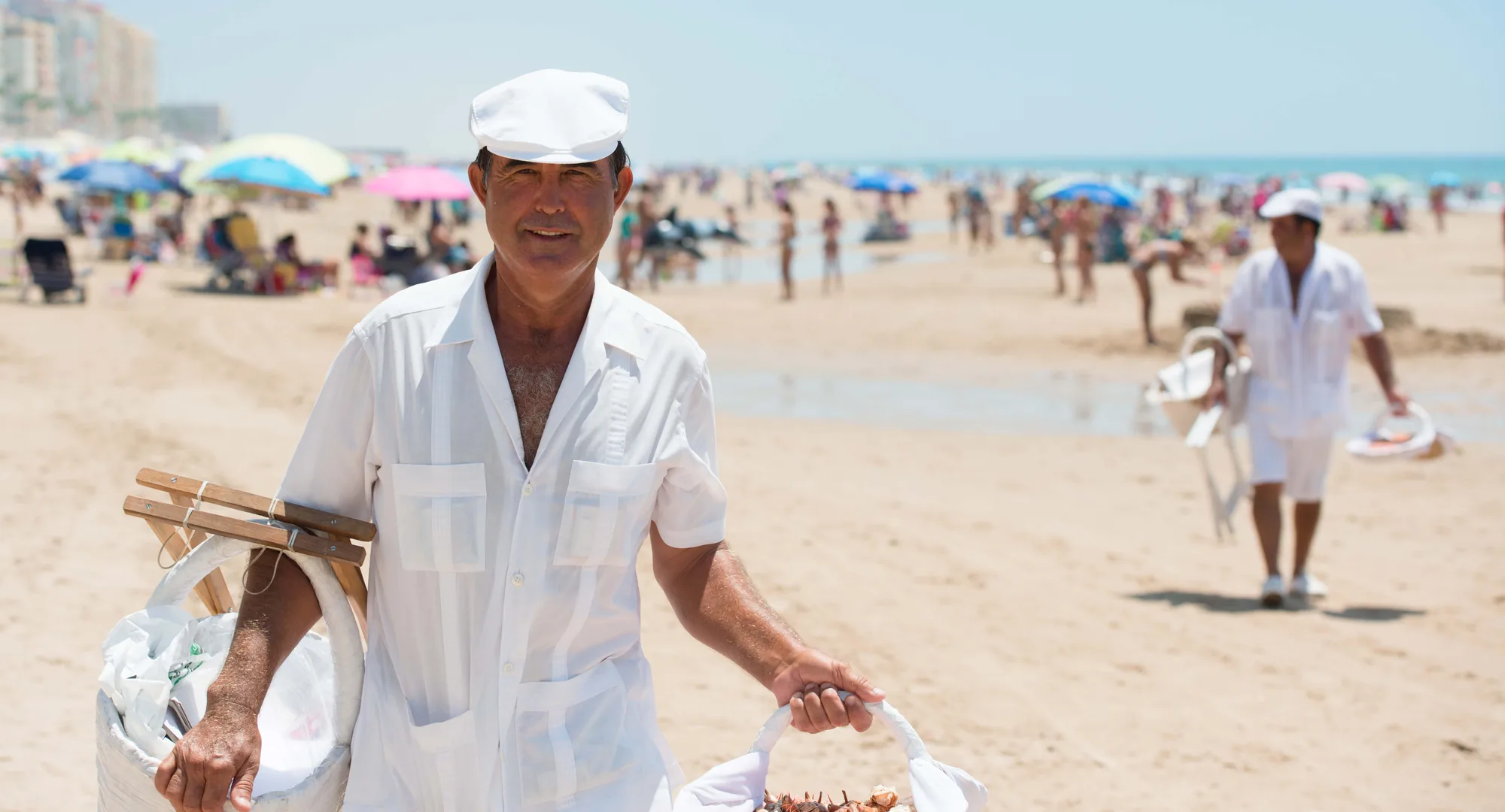 A local vendor walking on a bright Cádiz beach
