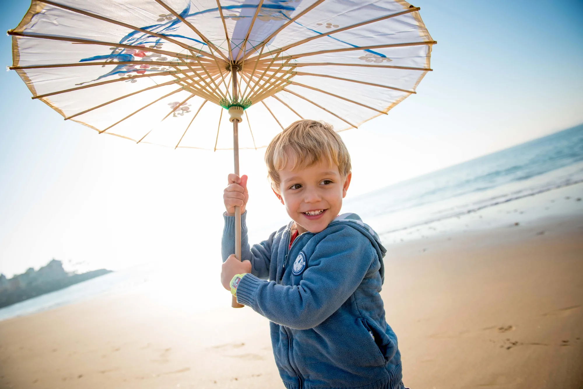 A child smiling under a beach parasol