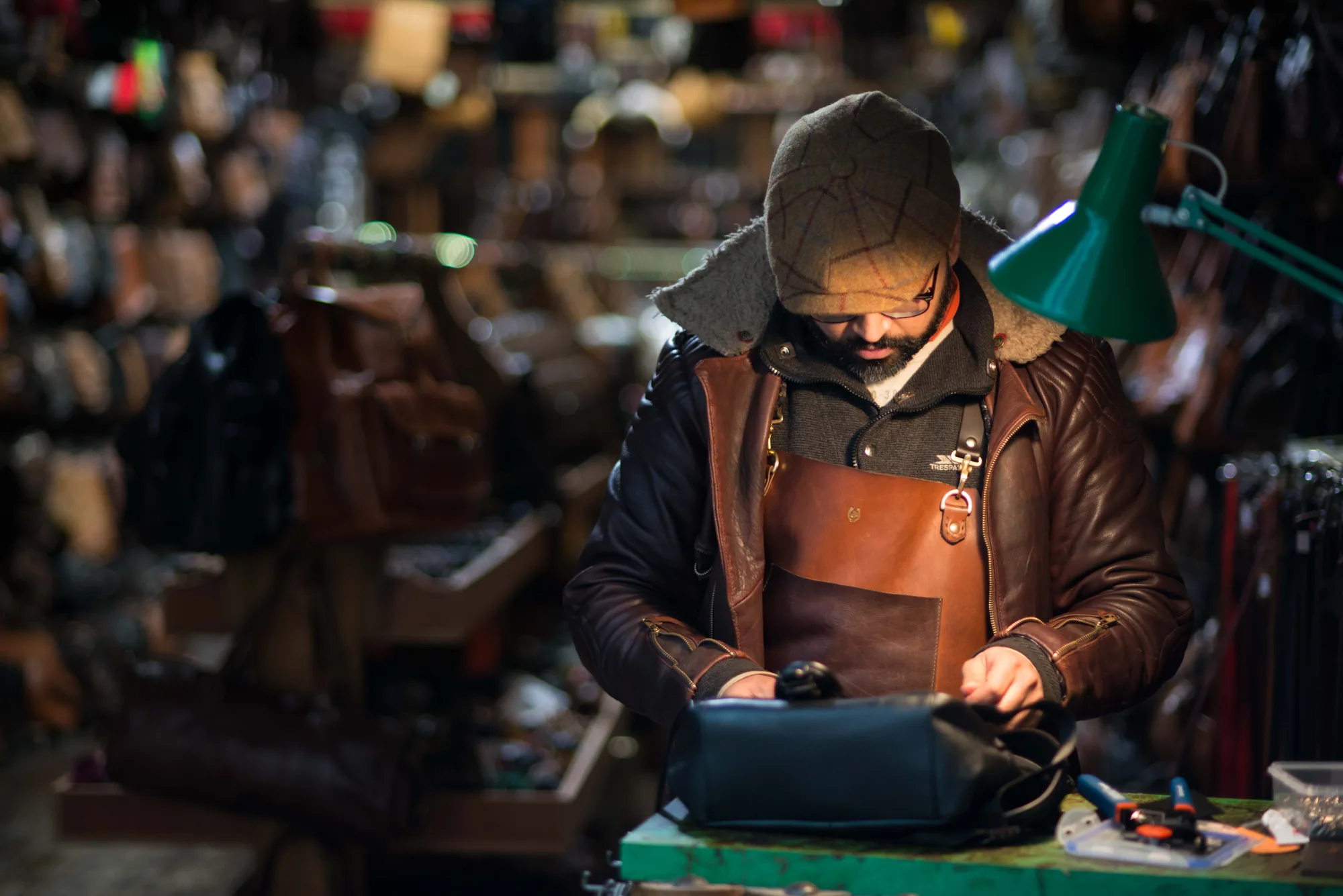 A leather craftsman concentrating at a market stall