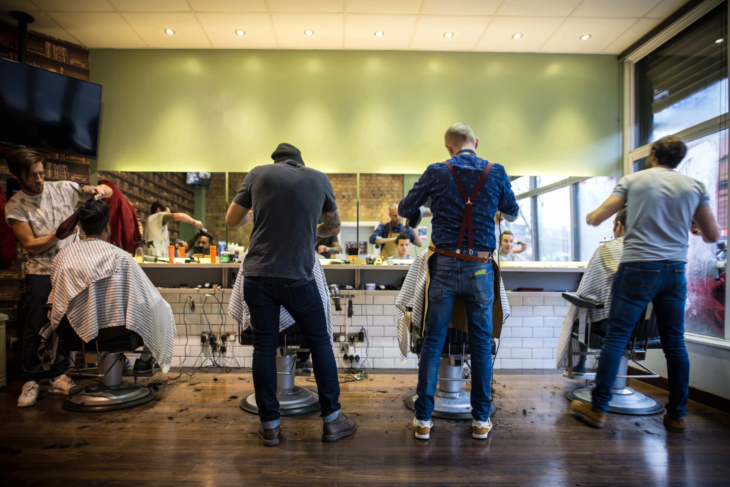 Four barbers working in parallel inside a London barbershop
