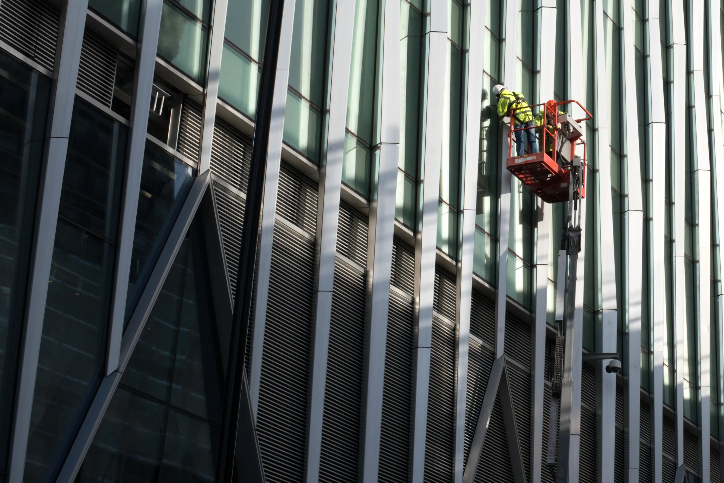 A rope-access worker suspended against a modern glass building