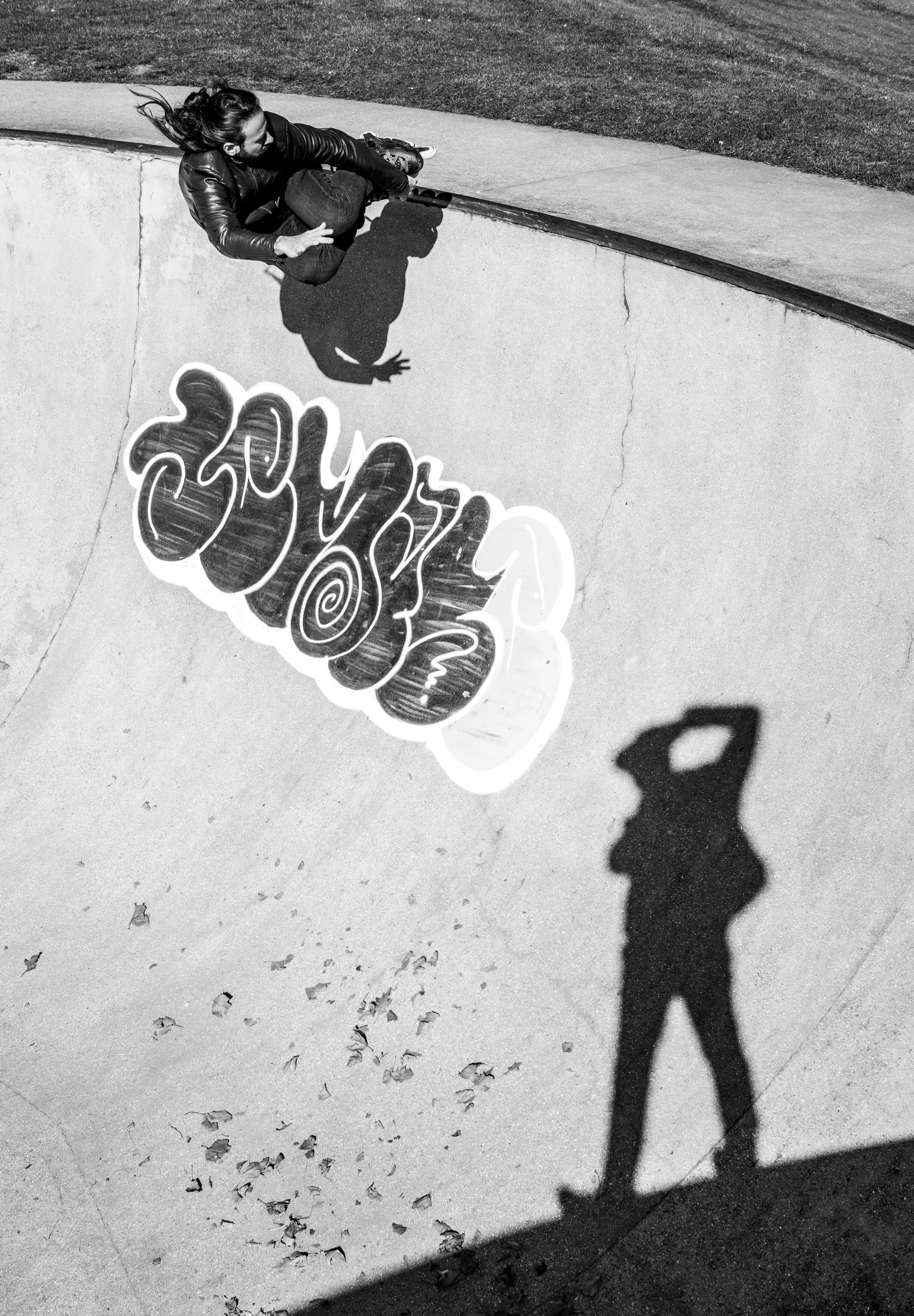A skateboarder carving through a concrete bowl above the photographer's shadow