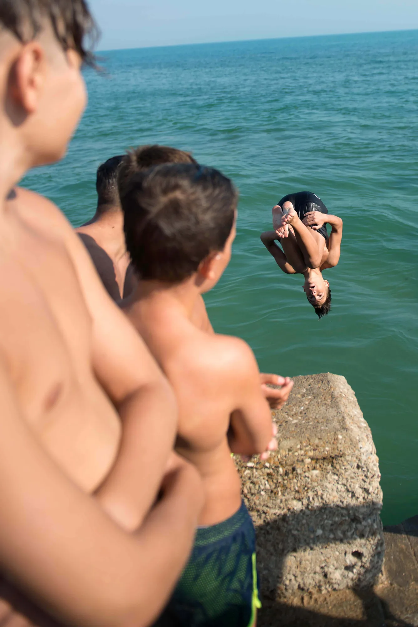 A swimmer diving into blue sea from a rock