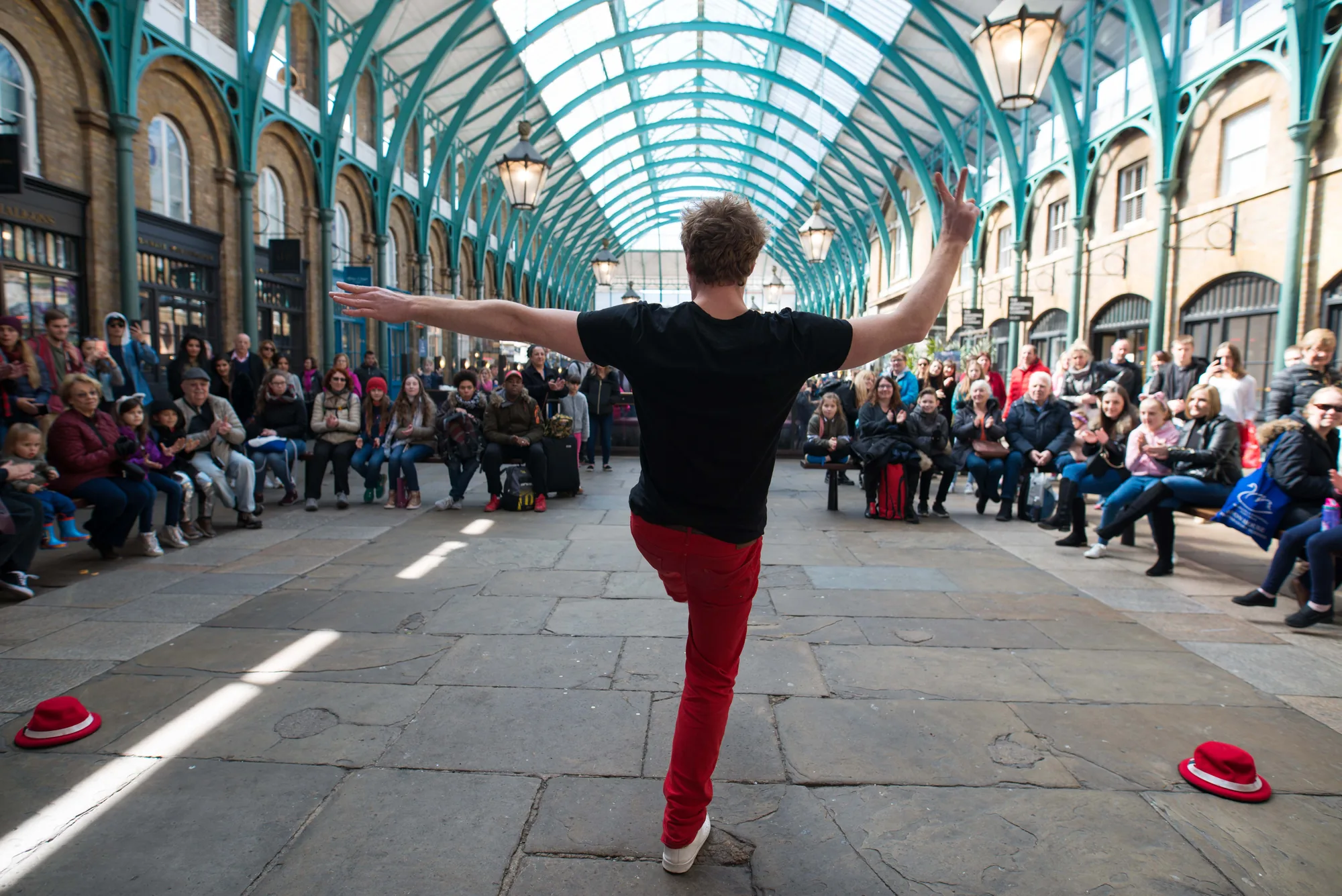 A street performer facing an audience beneath a glass arcade