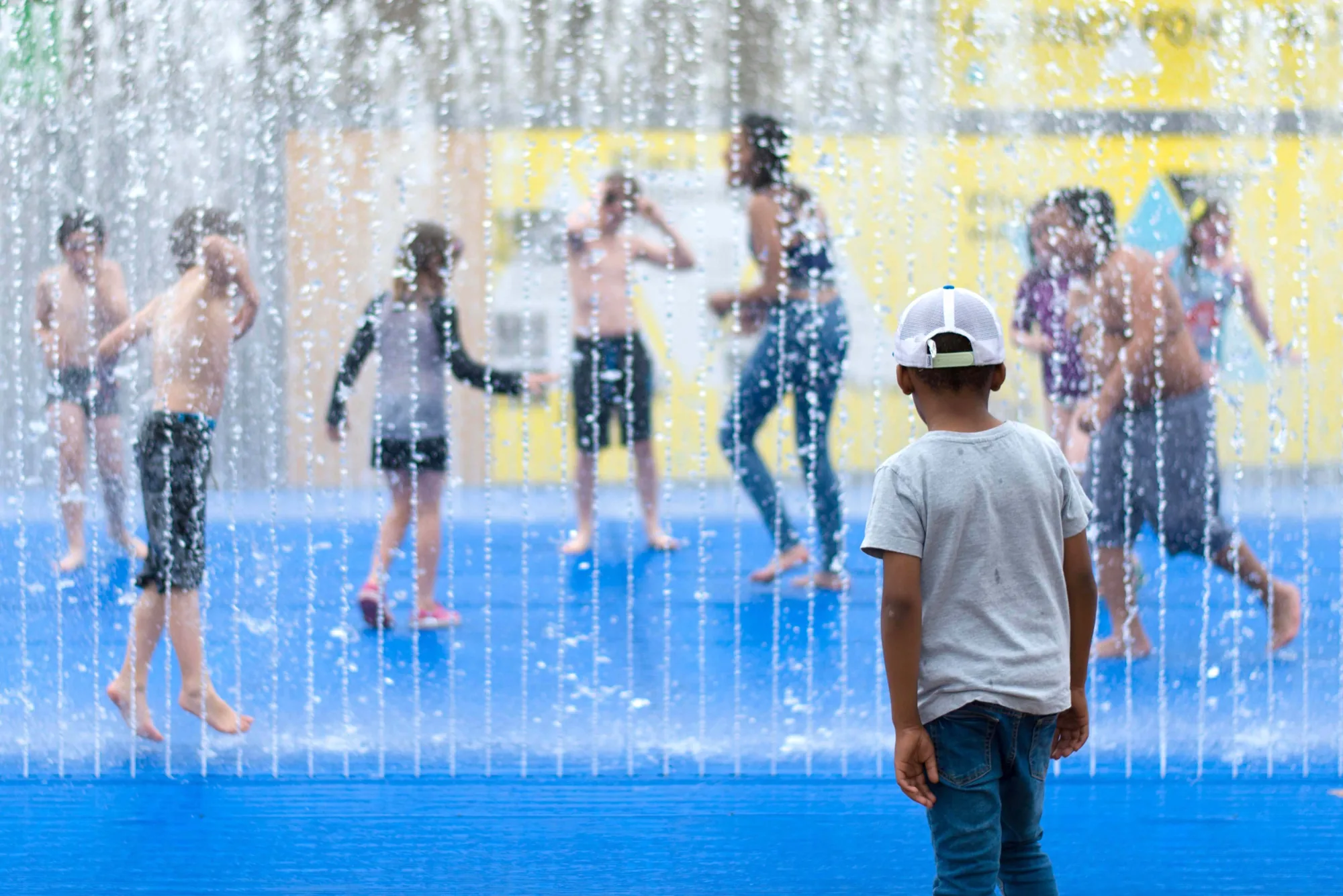 Children playing behind a curtain of fountain water